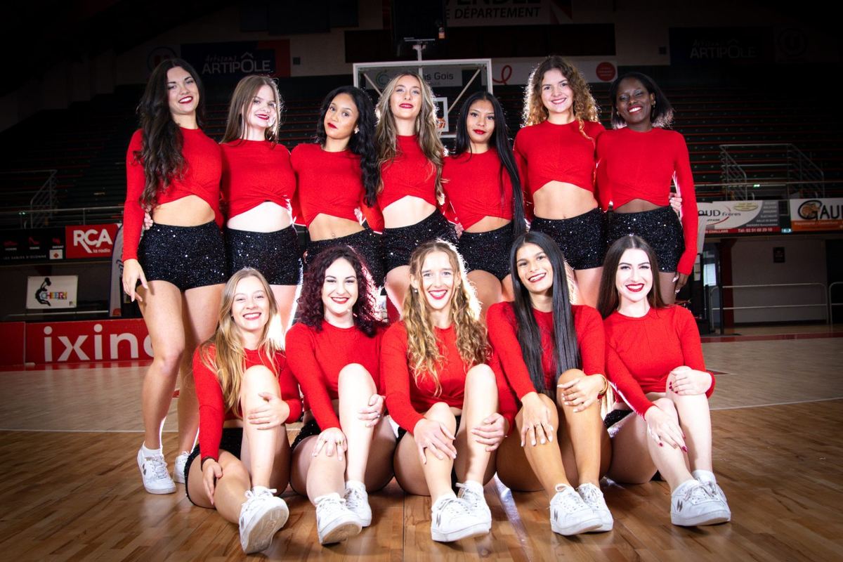 Les Cheery Dolls en tenue rouge, photo d'équipe sur un parquet de basket