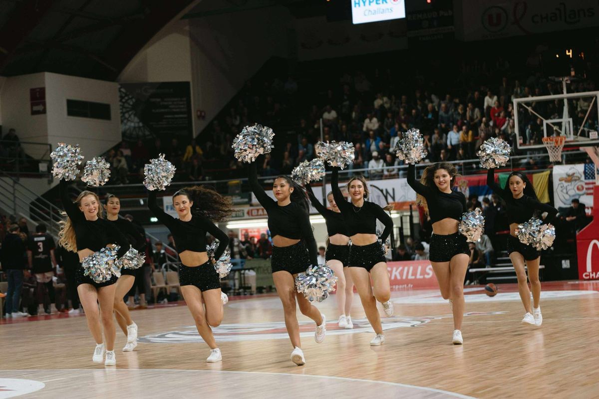 Saut des Cheery Dolls en tenue noire sur le parquet, devant le public