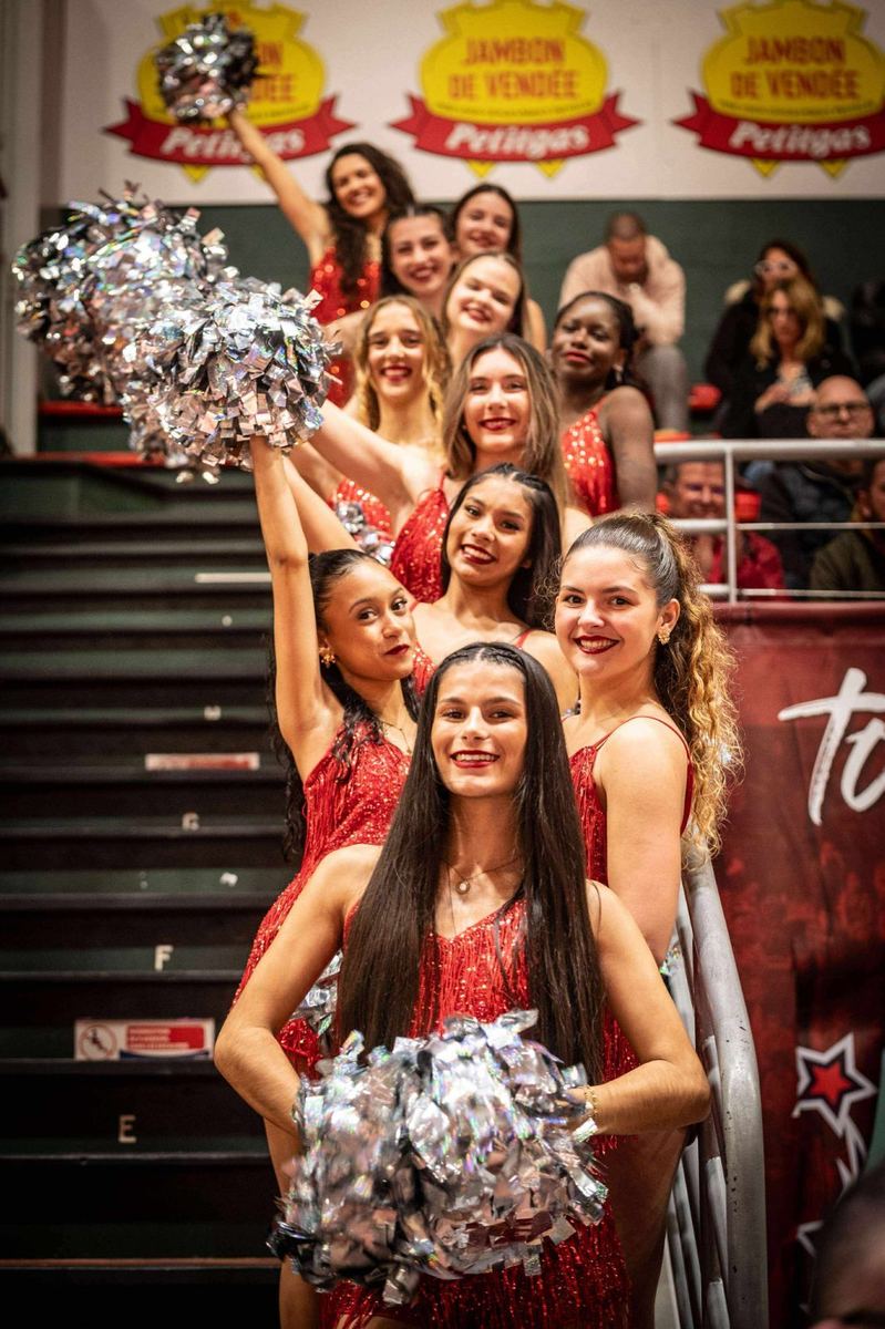 Cheerleaders en tenue rouge à paillettes avec pompons argentés dans les gradins